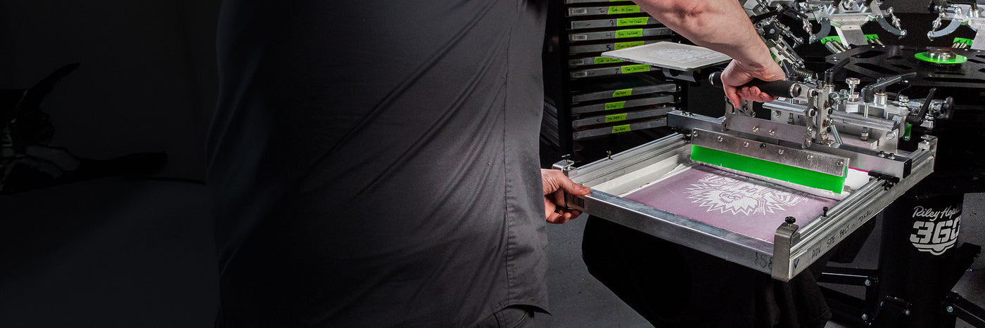 Operator using the Rudy Press on a Riley Hopkins 360 screen printing press.