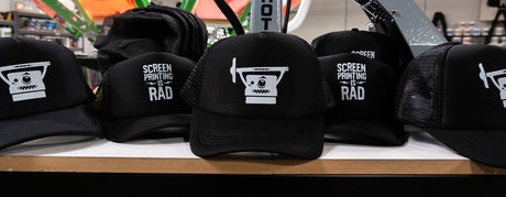 Several hats on a table with screen printed transfer designs