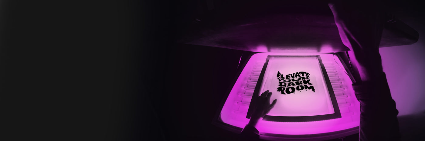 a film laying on a frame with the words Elevate Your Darkroom printed on it and being exposed with an exposure unit.