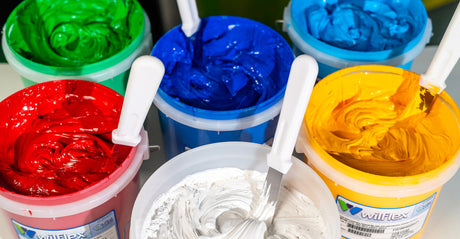 Colorful containers of Wilflex inks with mixing spatulas.
