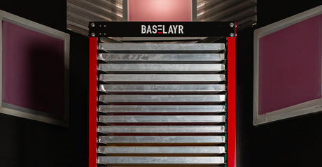 Baselayr screen drying rack with aluminum frames surrounded by pink coated screens in darkroom.
