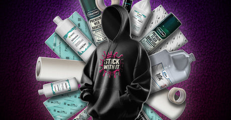 A black hoodie with a bright pink “Stick With It” graphic is surrounded by multiple screen printing adhesive products arranged in a circular pattern against a fleece texture background. 