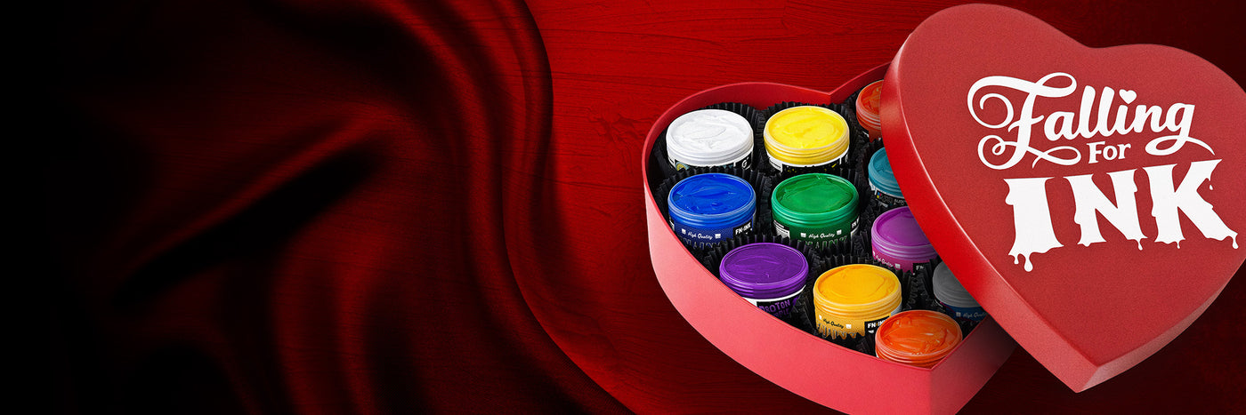 Open red heart-shaped gift box filled with colorful FN-INK and Green Galaxy Ink containers; the lid reads “Falling for Ink” on a wide red satin background.