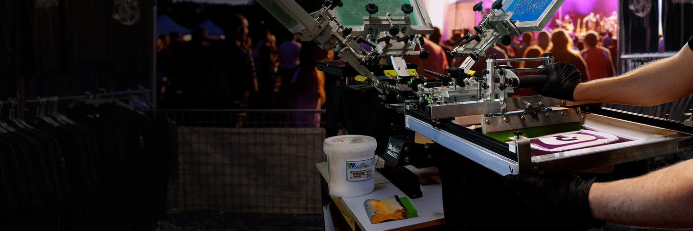 Wide view of a music festival merch station utilizing a Riley Hopkins 250 press and a Rudy Press guided squeegee system.